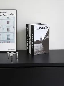 Decorative fake books set with London Paris New York print for modern home shelf decor details.