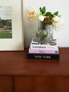 Modern minimalist decorative storage books set with ribbed glass vase and floral decor.