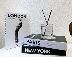 Close-up detail of modern decorative fake books and glass diffuser set for interior styling.