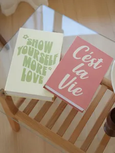 Detail view of decorative fake books with English quotes on glass table for home styling.