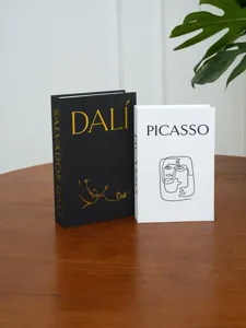 Detail view of minimalist artistic decorative fake books with Dali and Picasso designs on wooden table.