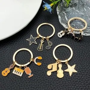 Λεπτομέρεια μπρελόκ μουσικού θέματος με charms κιθάρας πιάνου και νότας σε χρυσό.