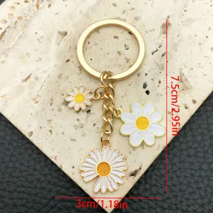 Portachiavi in metallo dorato con ciondoli margherita in smalto bianco, accessorio borsa