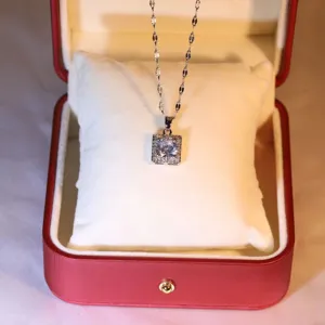 Detailed view of a sparkling square zircon pendant necklace displayed inside a red jewelry box.