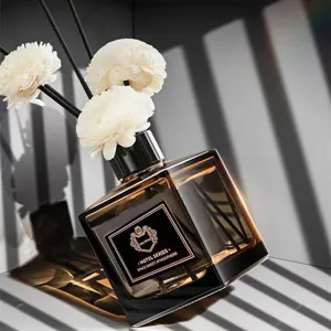Flacon diffuseur de parfum en verre carré avec bâtonnets de fleurs blanches pour maison.