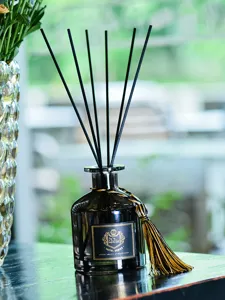 Gros plan d'un flacon de diffuseur en verre noir avec bâtonnets noirs et pompon, parfum d'intérieur.