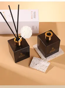 Detailed view of the square brown glass aromatherapy diffuser bottle with black reeds and flower.