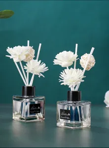 Detailansicht der quadratischen Glas-Duftstäbchen-Flasche mit weißen Blumen für den Raum.