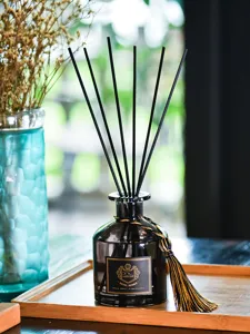 Gros plan sur le flacon de diffuseur de parfum en verre noir avec plateau et fleurs séchées.