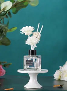 Detailansicht der Duftdiffusor-Flasche, weiße Blumen-Rattan-Stäbchen, elegante Raumdeko.