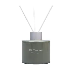 Bottiglia diffusore di fragranza in ceramica verde con bastoncini bianchi per la casa.