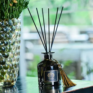Diffusore di aromi per ambiente in vetro nero con bastoncini e nappa dorata elegante.