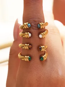 Closeup detail of stacked gold twist rings featuring colorful natural stones and pearls.