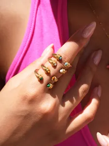 Close-up detail shot of stacked gold twisted cable rings featuring colorful natural gemstone cabochons.