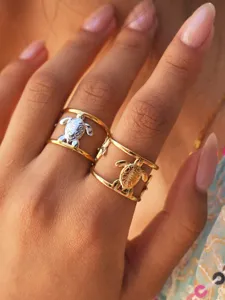 Primo piano dettagliato di anelli aperti con design tartaruga marina raffinati a mano.