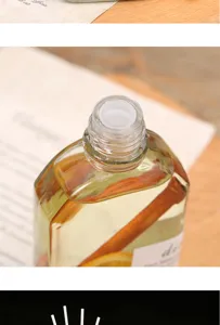 Close-up detail of the glass reed diffuser bottle featuring botanical fillings and clear open neck.