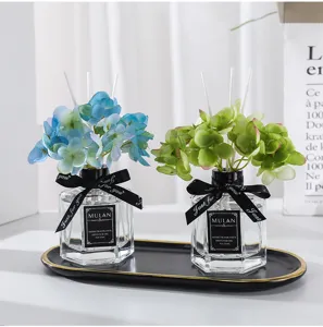Set aus Duftstäbchen für das Zuhause mit künstlichen blauen und grünen Hortensien und Ölflaschen.