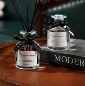 Close-up detail of glass reed diffuser bottle with black sticks and elegant ribbon bow.