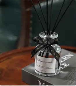 Close-up detail of reed diffuser bottle with black sticks and elegant ribbon decoration.