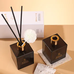 Luxury reed diffuser set with elegant brown glass bottles, black reeds and white floral decor.