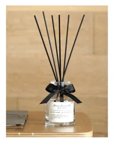 Nahaufnahme schwarzer Duftstäbchen in einer Glasflasche mit Schleife und Duftetikett.
