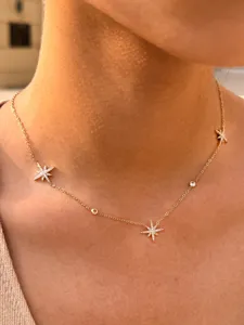 Close-up detail of delicate stainless steel gold star station necklace with sparkling CZ stones.