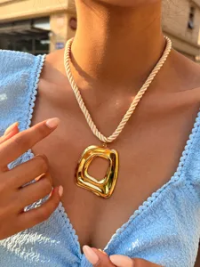 Close-up opname van een unieke dikke geometrische vierkante hanger ketting met touwketting.