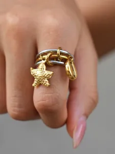 Nahaufnahme Detail des mehrschichtigen Edelstahlrings mit süßen Seestern- und Muschelanhängern.