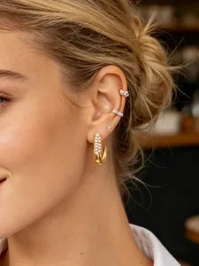 Detailed close-up of a stylish gold J-shaped pave diamond hoop earring worn on a pierced ear.