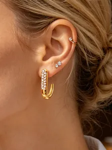 Close-up detail of J-shaped gold-toned hoop earrings embedded with sparkling rhinestones for women.