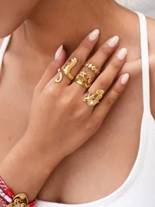 Goldenes Meeresmotiv Ring Set Detail mit Seepferdchen Palme Muschel Design an Modellhand.