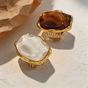 Bagues rétro en résine ambre et blanche irrégulière avec acier titane doré, détail.