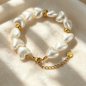 Elegantes herzförmiges Perlenarmband mit goldenen Metallperlen und Verlängerungskette.