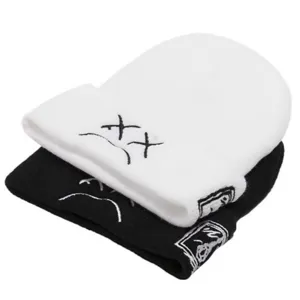 Detailed view of black and white knitted beanies with embroidered cute face design, winter warm hat.