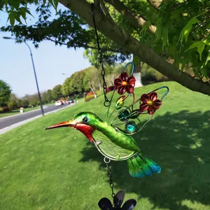 Metal hummingbird hanging ornament with glass body and flower wings for garden decor detail.