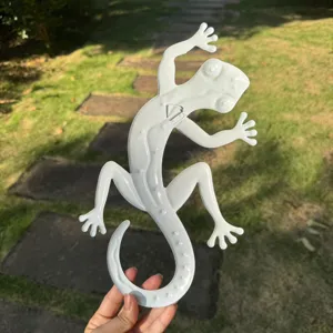 Detail view of white metal gecko wall art, hanging lizard sculpture for garden and home decor.