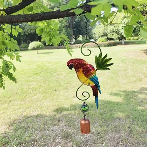 Close-up detail of the colorful iron parrot wind chime hanging outdoors on a green tree.
