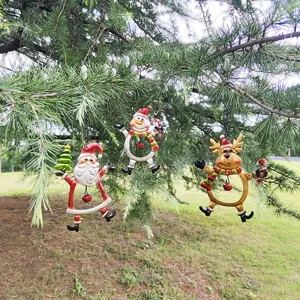 Outdoor close-up shot of painted iron Christmas ornaments hanging on a natural pine tree branch.