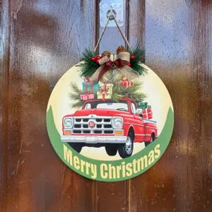 Wooden Christmas hanging sign detail showing vintage red truck design with pine decor.