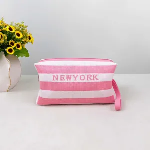 Détail de la trousse en tricot rayé rose et blanc, avec des coutures propres et une poignée.