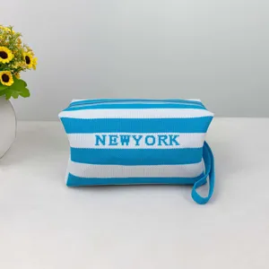 Trousse de toilette tricotée à rayures bleues et blanches avec dragonne et lettrage NEWYORK.