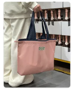 Foldable waterproof shopping tote bag detail view, lightweight pink grocery bag with drawstring.