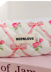 Quilted cosmetic bag detail featuring pink roses and bows pattern with fabric brand label.