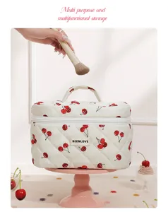 Detailed view of quilted cherry cosmetic bag, portable makeup organizer with handle and cherry print.