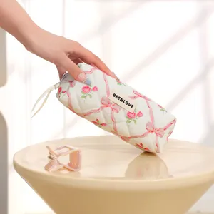 Quilted cosmetic bag with pink bow and rose floral print, portable makeup brush storage pouch.