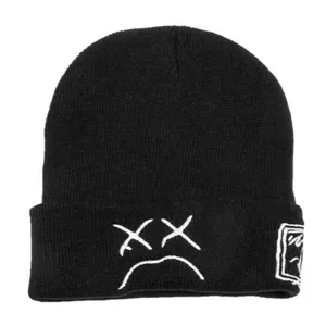 Black knitted beanie hat with white embroidered sad face design, casual winter warm cap.