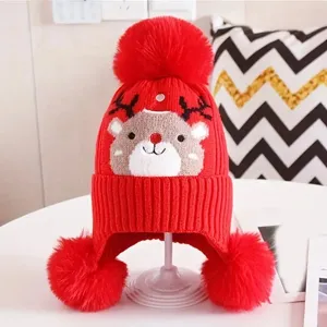 Children winter warm red knit hat with cute reindeer pattern and three fluffy pom poms.