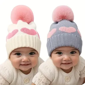 Baby winter knit hat detail view featuring sweet heart pattern and fluffy pink pompom.