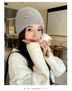 Detail view of grey knitted beanie hat with metal accent, cozy winter style in cafe.