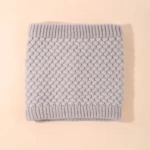 Primo piano di un accogliente scaldacollo in maglia grigia con elegante trama lavorata.